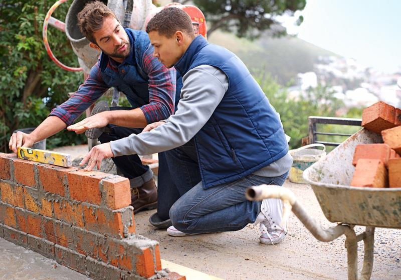 Making strong foundations - Teaching the basics. Shot of bricklayers at work.